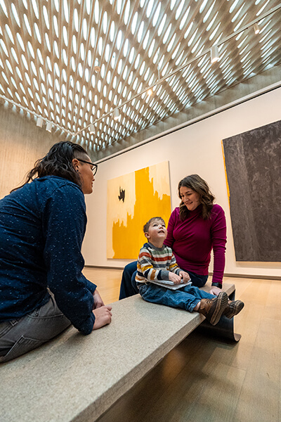 A family sits on a bench and looks at each other and the ceiling