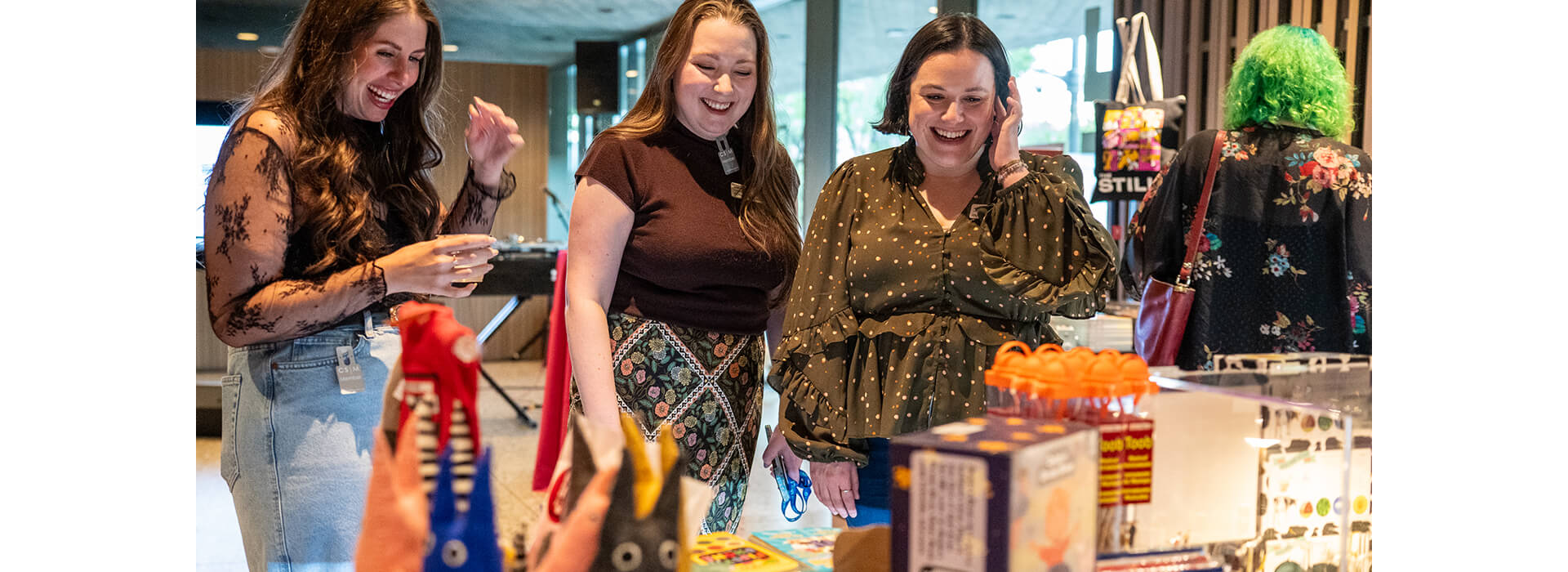 Three women looks at merchandise on a table at the Clyfford Still Museum Shop