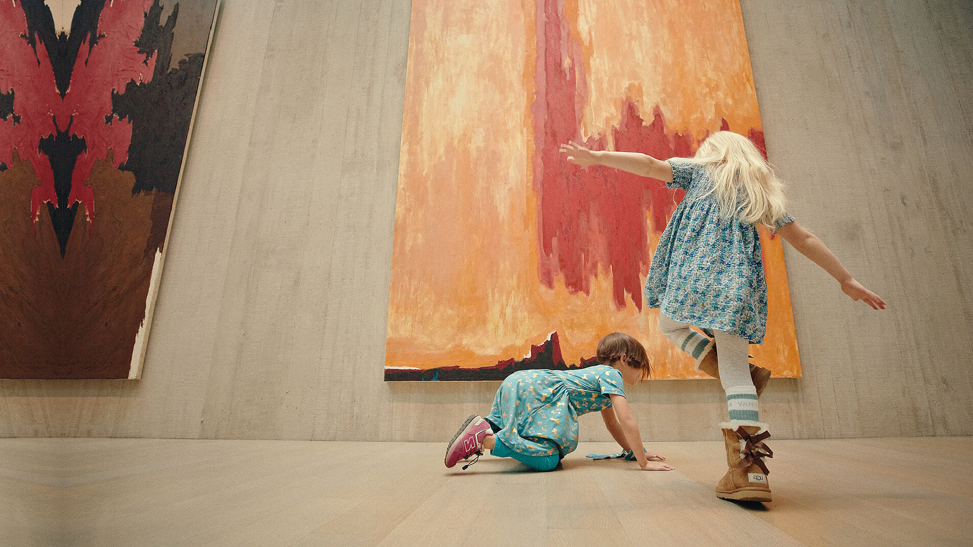 Two girls pose in front of a painting