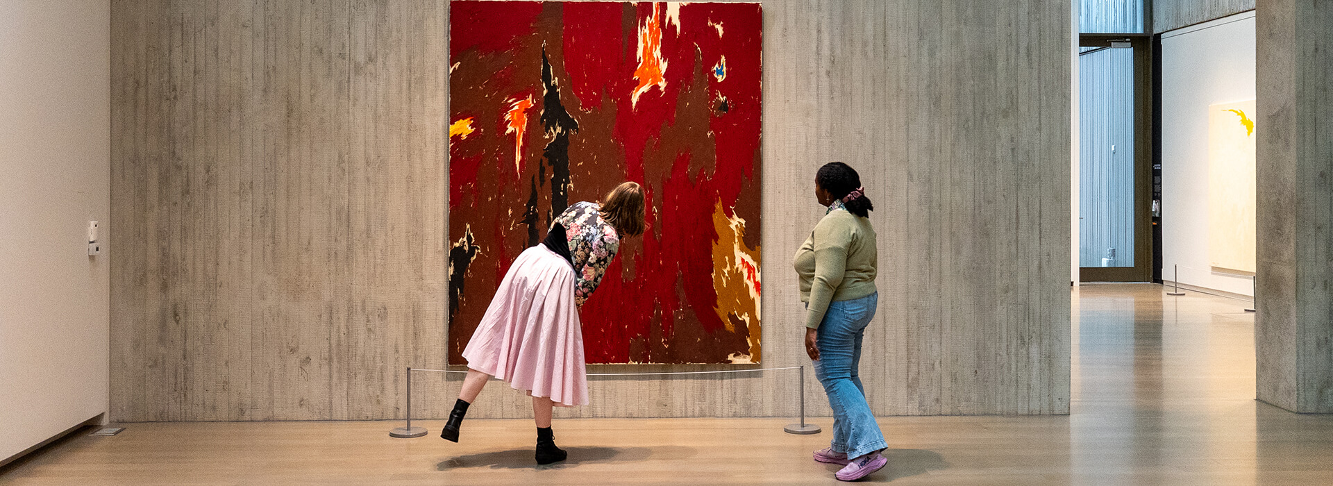 Two women look at a red abstract painting