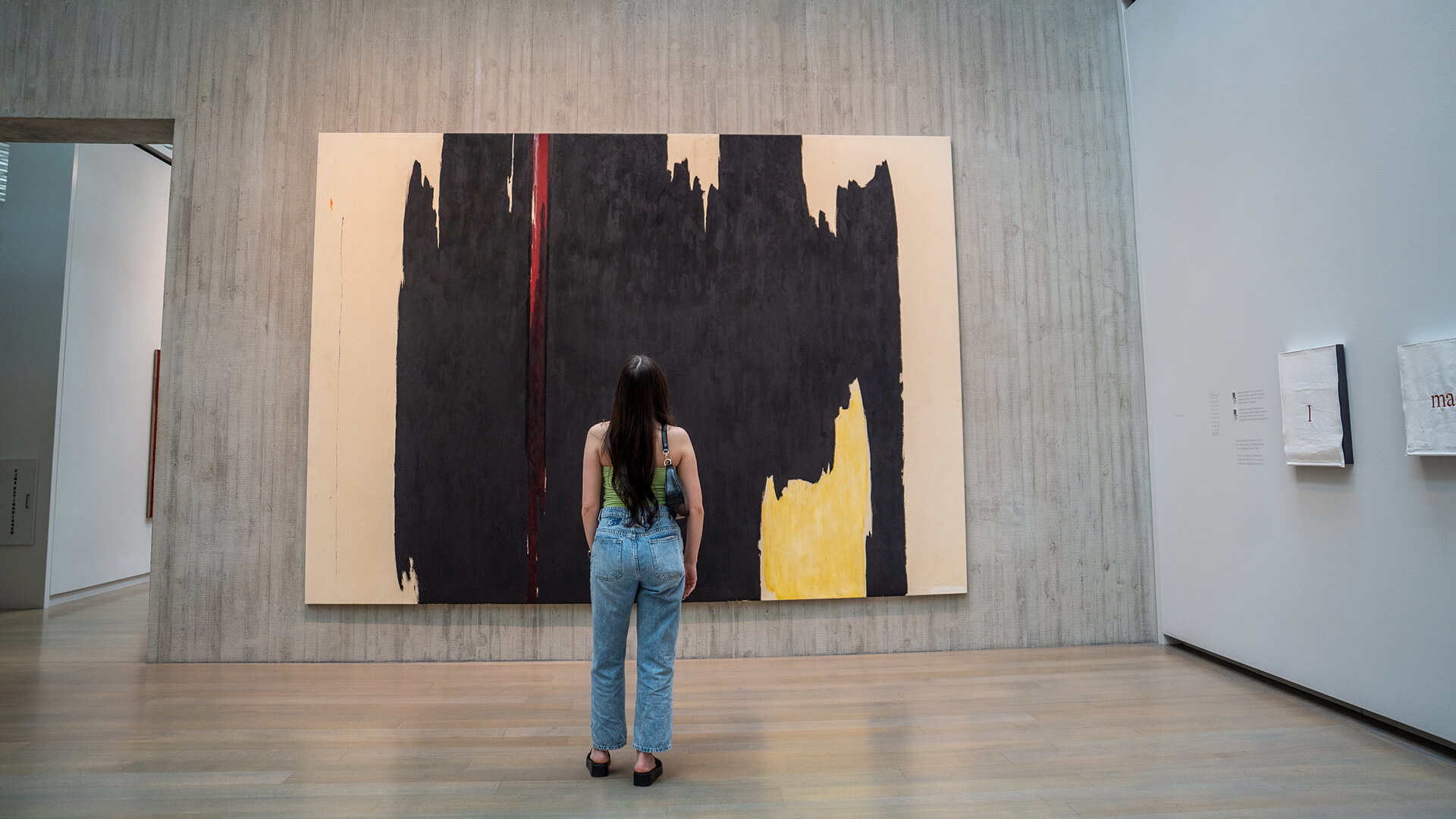 A woman looks at a large abstract painting on the wall