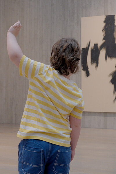 A young boy makes shapes he sees in a painting