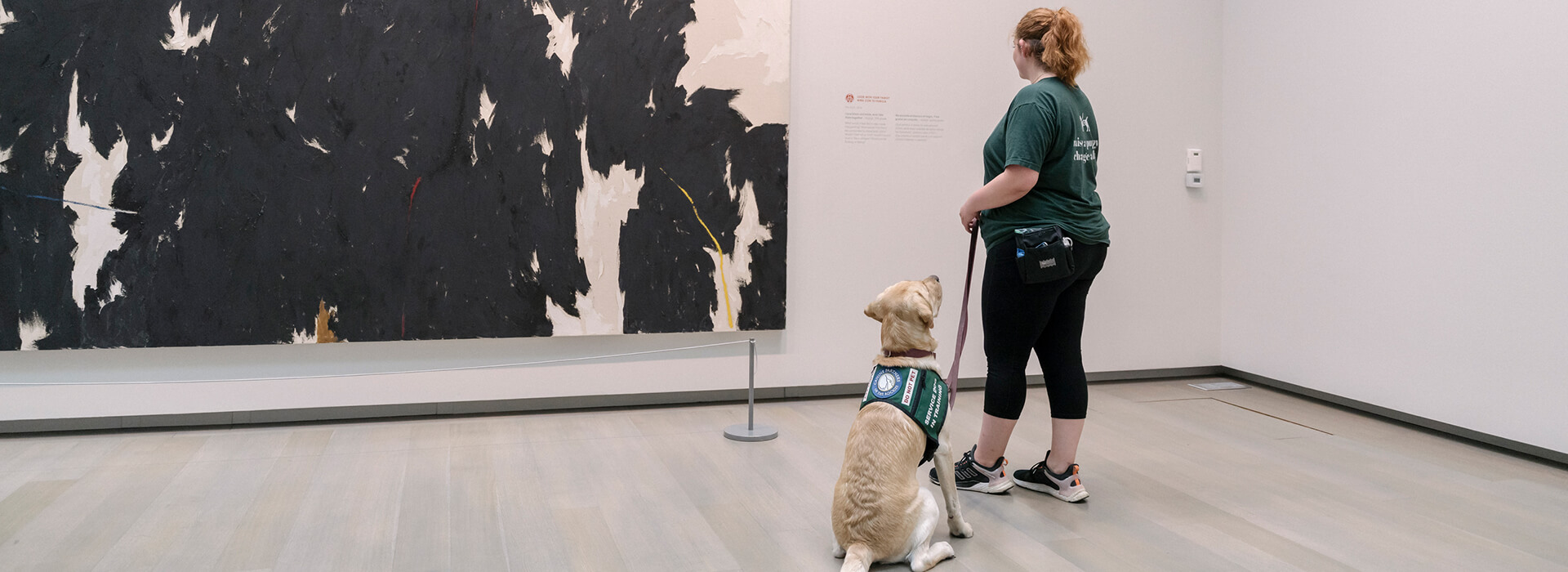 A woman and service dog look at the art