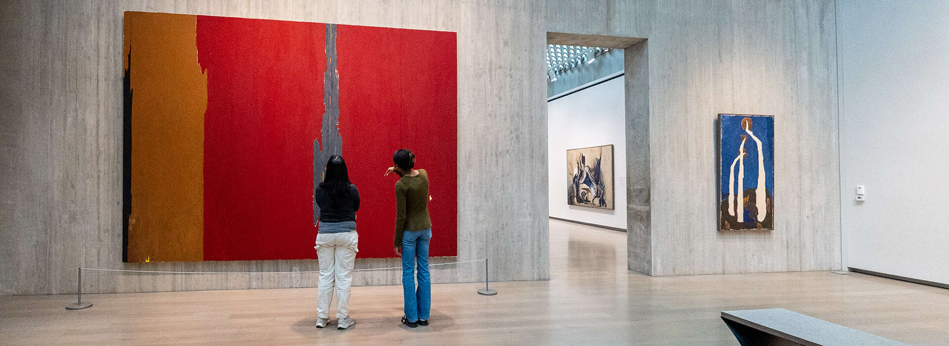Two women look at a large red painting
