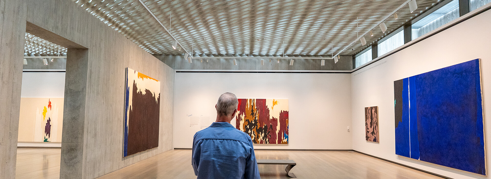 A man stands at the entry of a gallery and looks at art