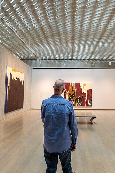 A man stands at the entry of a gallery and looks at art