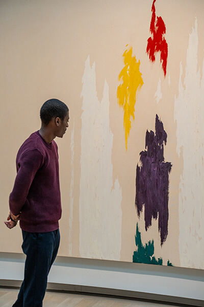 A man looks at a colorful abstract painting