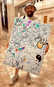 A man holds up a large board with doodles on it