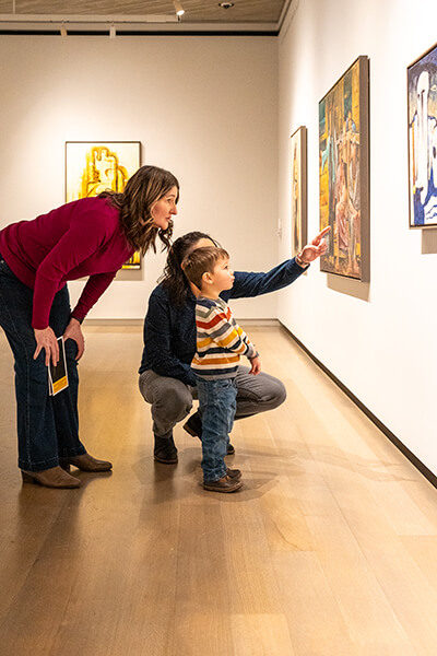 A family looks at a painting on the wall with their young child