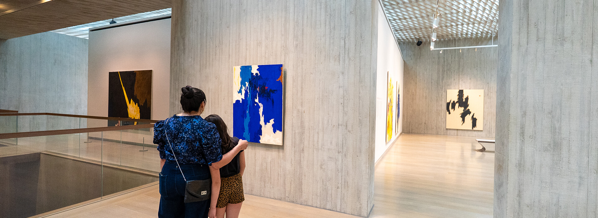 A woman and her daughter look at a blue painting