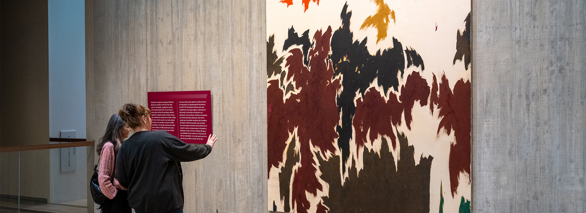 Two women look at a large abstract painting