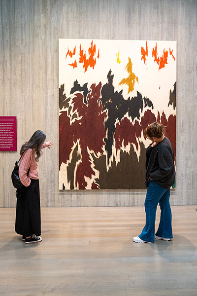 Two women look at a large abstract painting