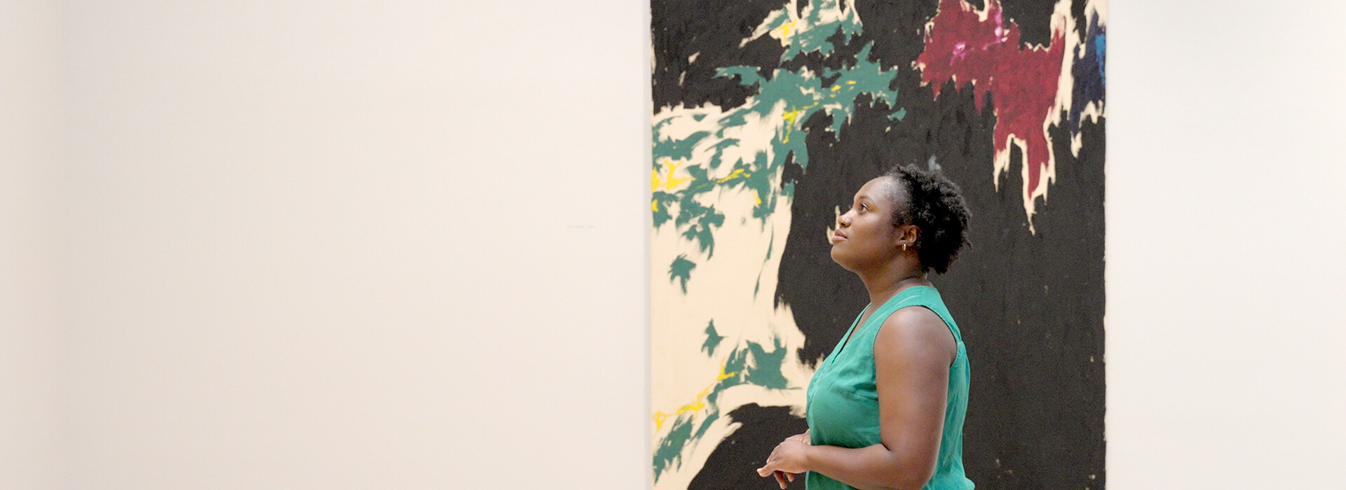 A woman stands in front of a colorful abstract painting