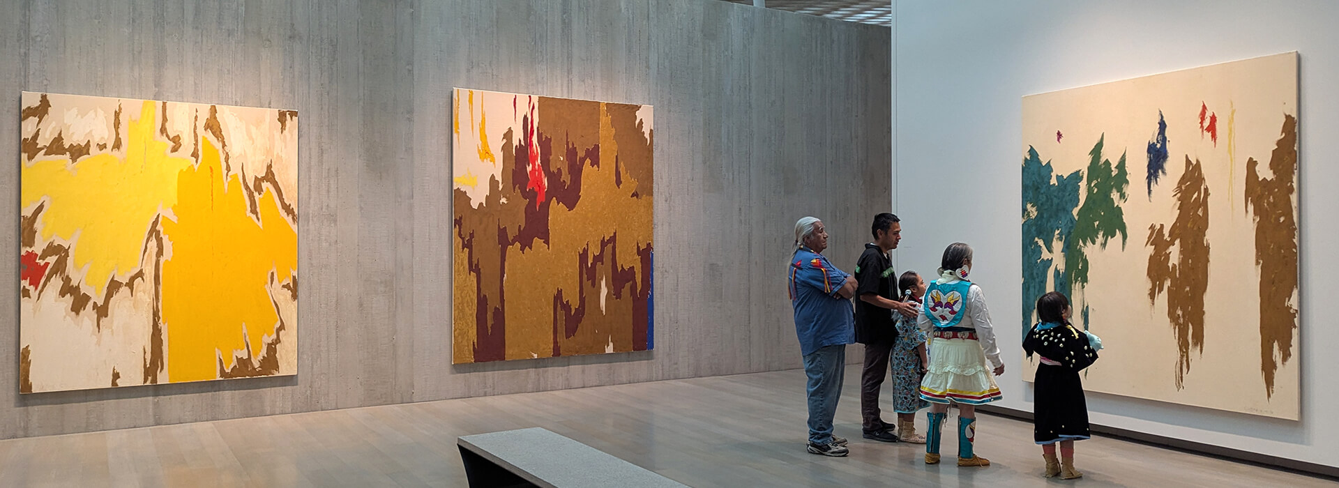 A family in traditional Native regalia looks at art at the Clyfford Still Museum