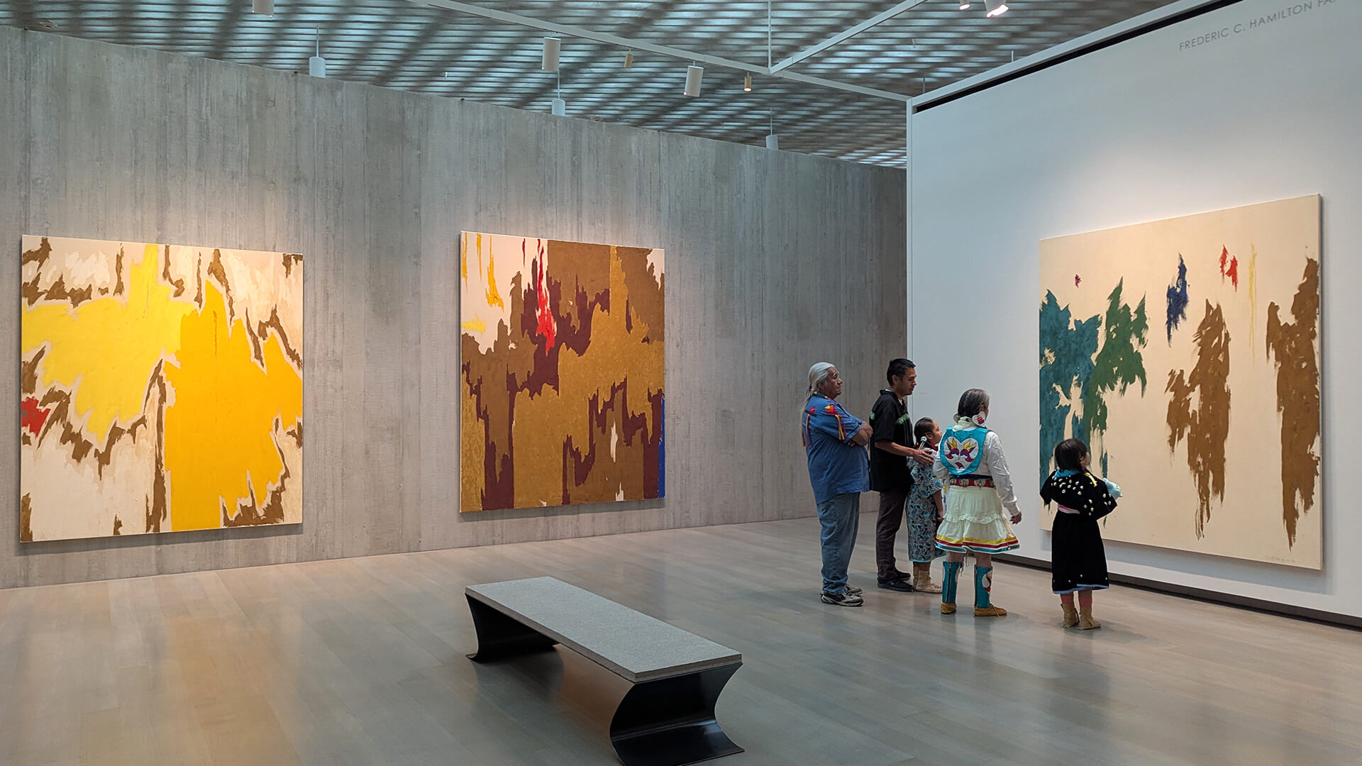 A family in traditional Native regalia looks at art at the Clyfford Still Museum