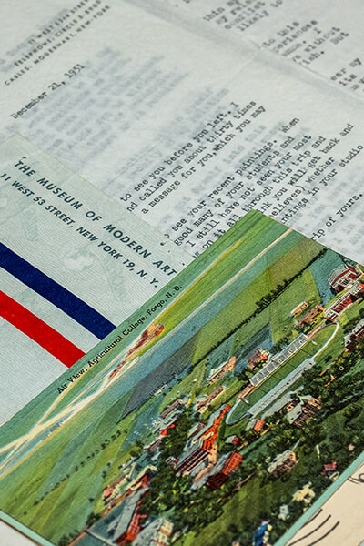 Pile of typed and handwritten letters, envelopes, and a postcard