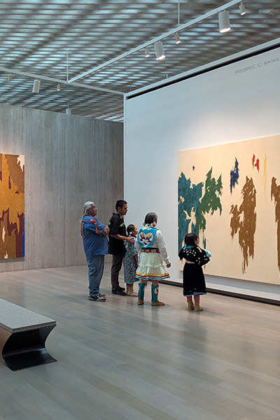 A family in traditional Native regalia looks at art at the Clyfford Still Museum