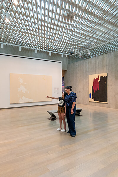 A child and her mom look at art