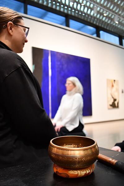 Closeup of a meditation bowl in focus with people meditating behind