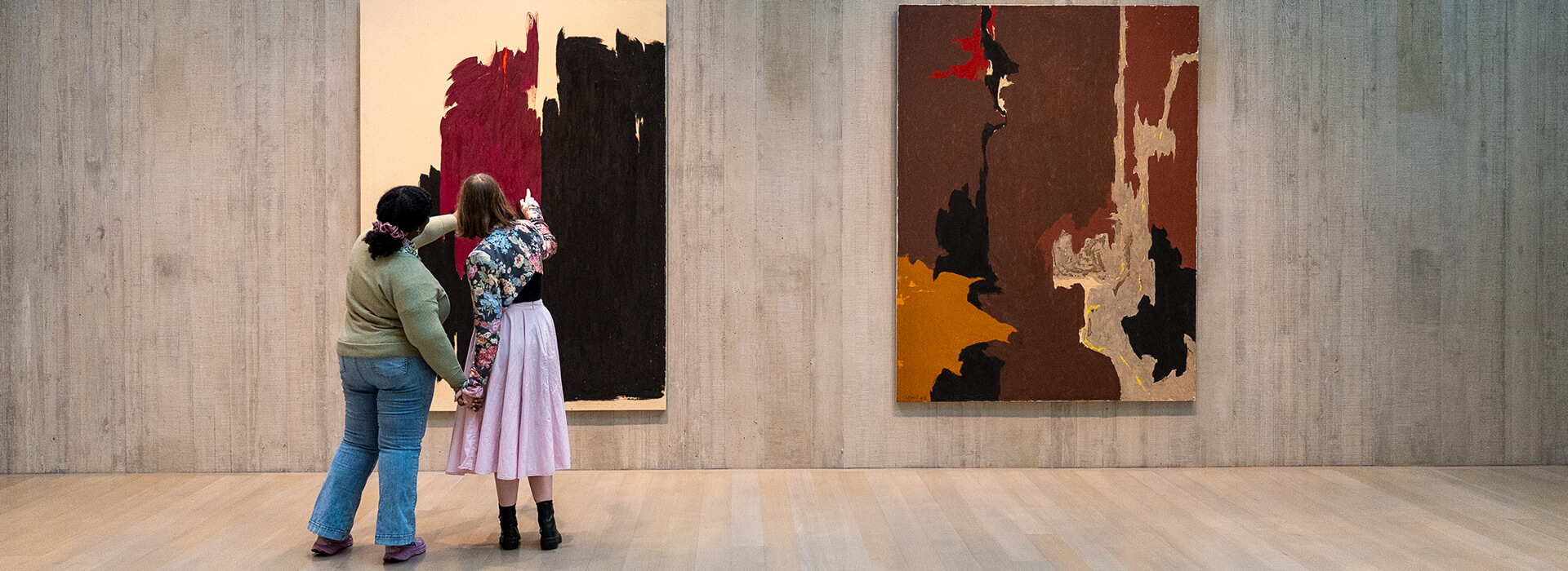 Two people hold hands and point at a painting