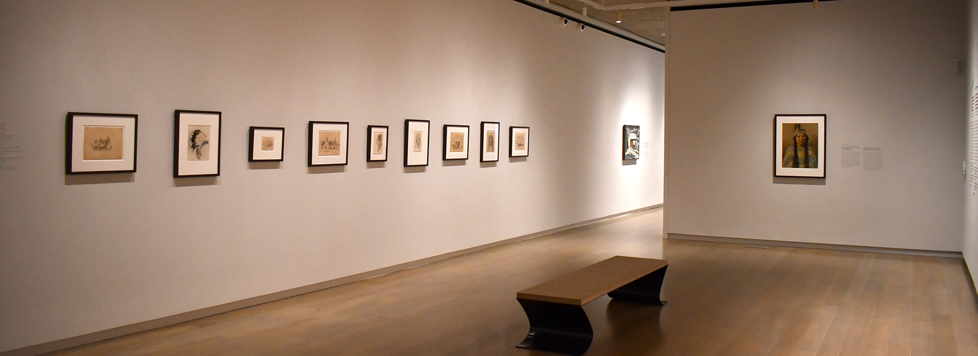Installation view of a gallery with small framed drawings on the walls