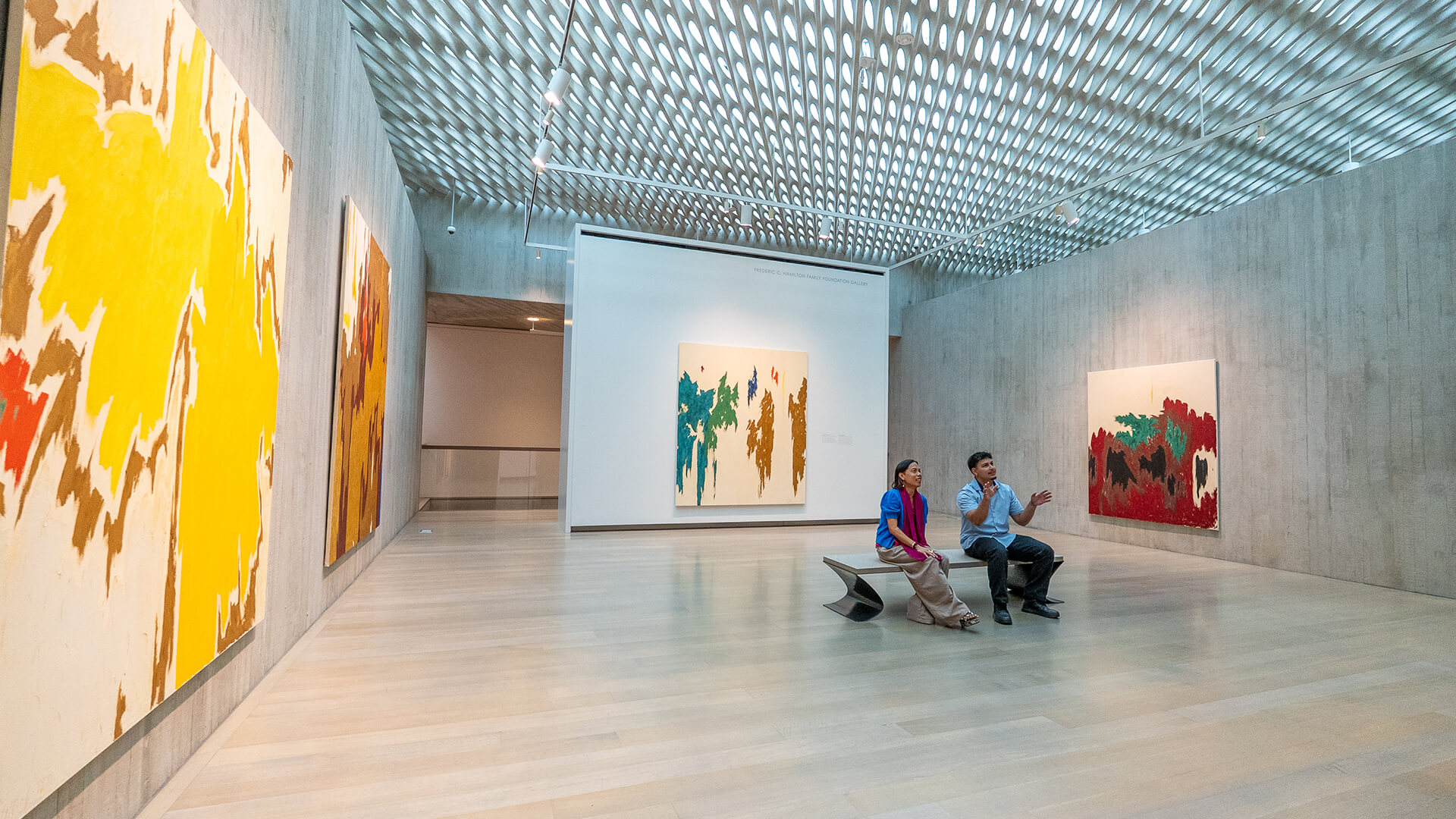 Tell Clyfford I Said 'Hi' Two people sit on a bench and look at art