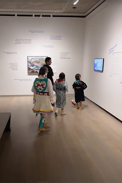 A family looks at a video screen on the wall in a gallery