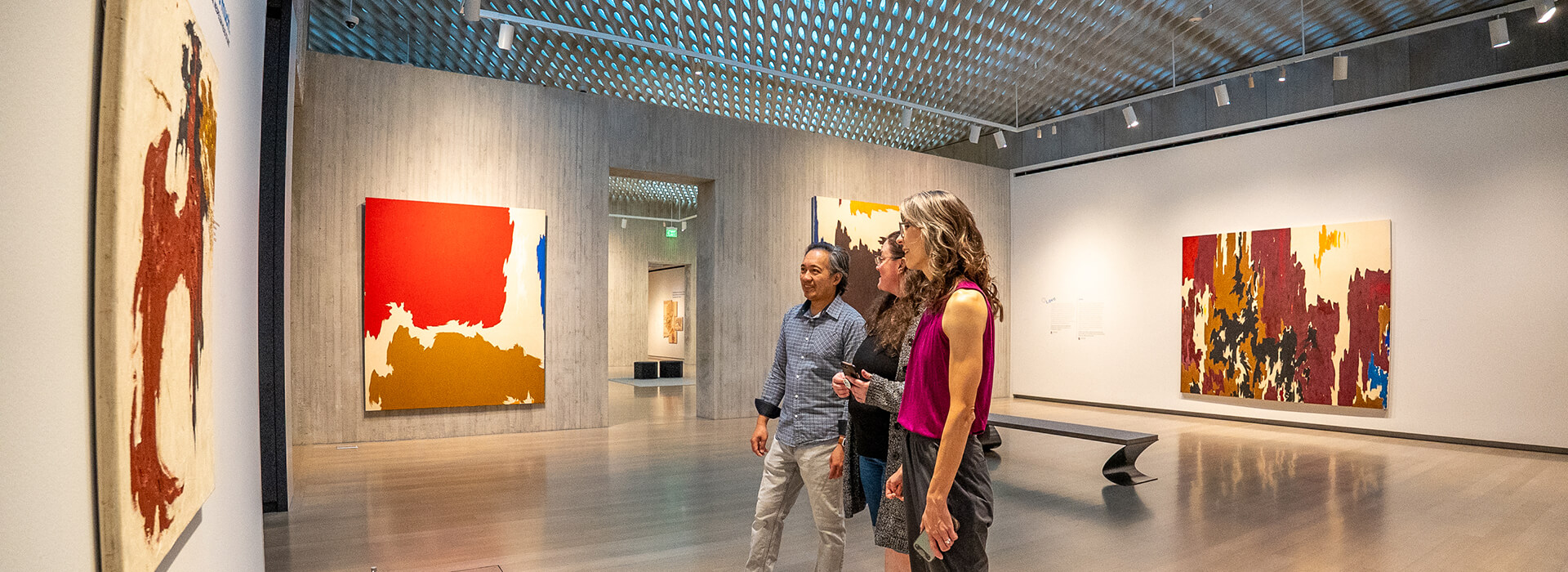 Three people look at artwork