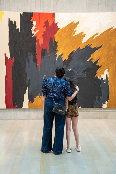 Two people look at a large abstract painting