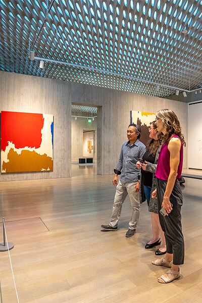 Three people look at artwork