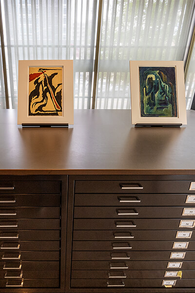 Two works on paper sit on top of file drawers