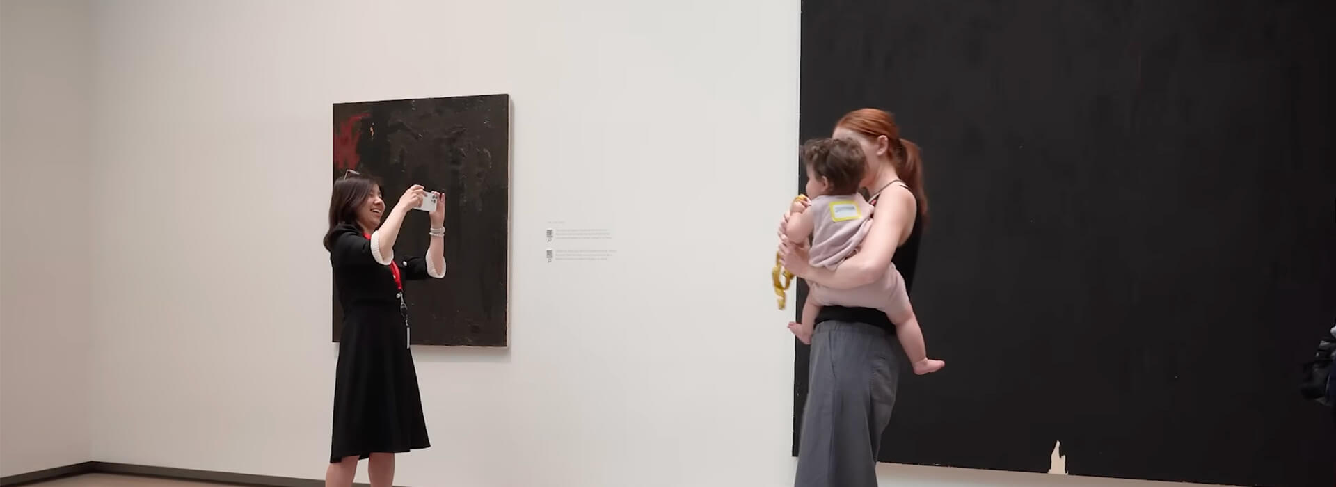 A woman holds an infant as another woman takes a photo with her phone