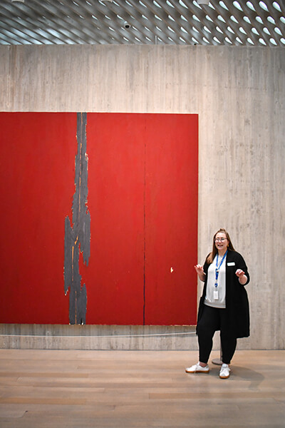 A woman points at a large red abstract painting