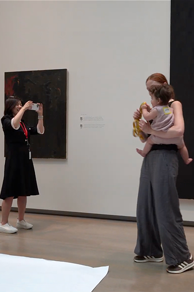 A woman holds an infant as another woman takes a photo with her phone