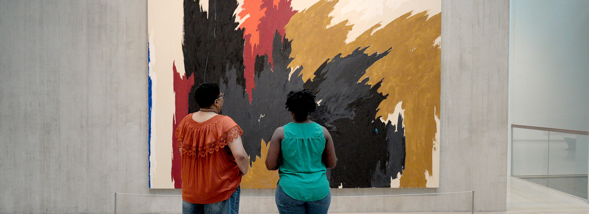 Two women look at a large colorful painting