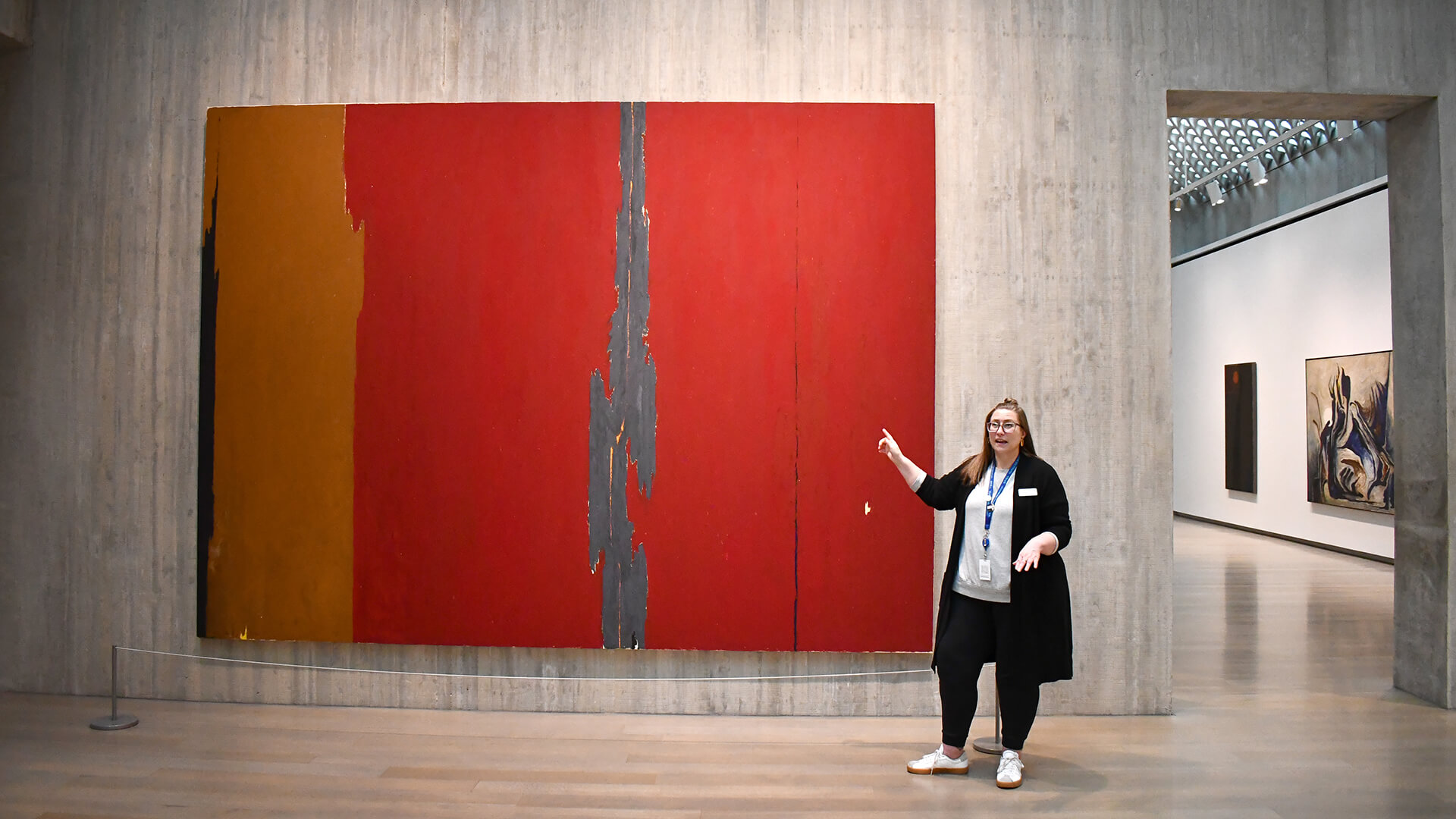 A woman points at a large red abstract painting
