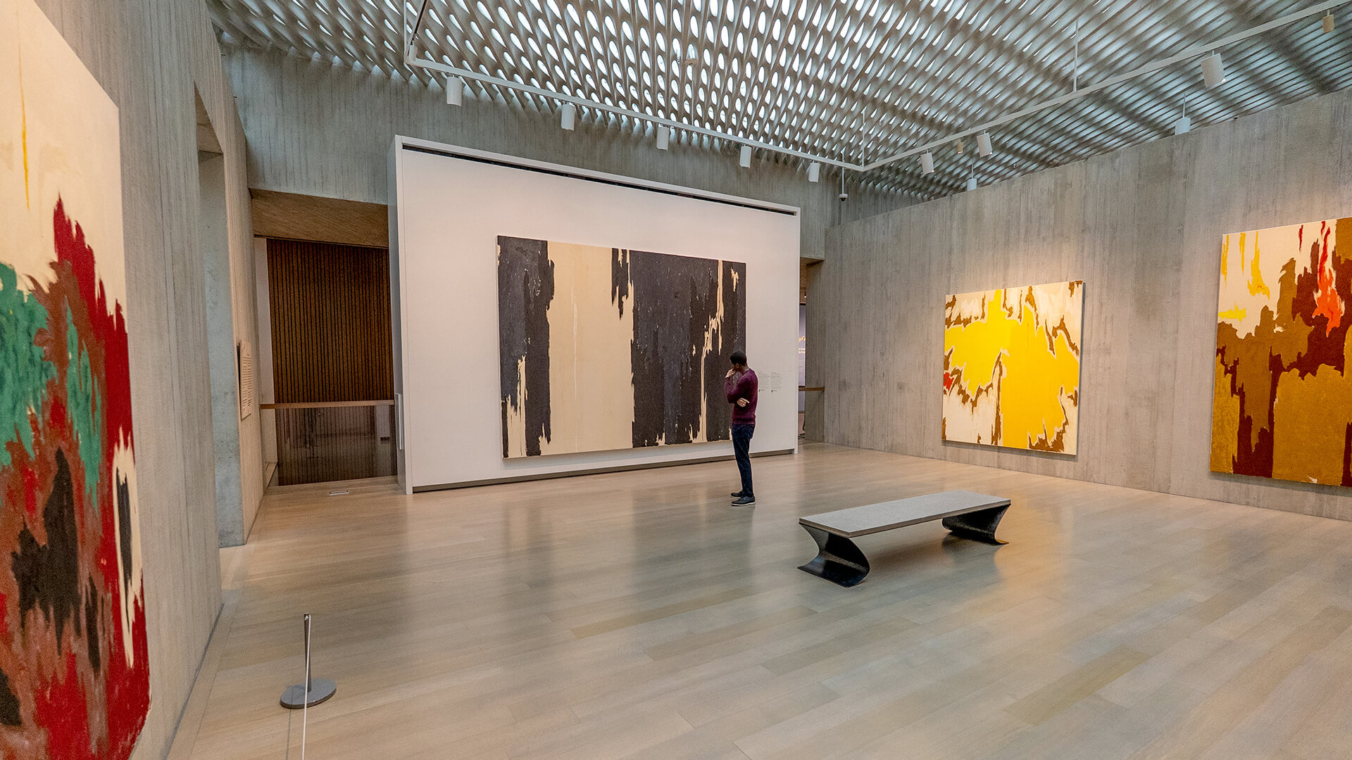 A man looks at a large black and white painting in a gallery