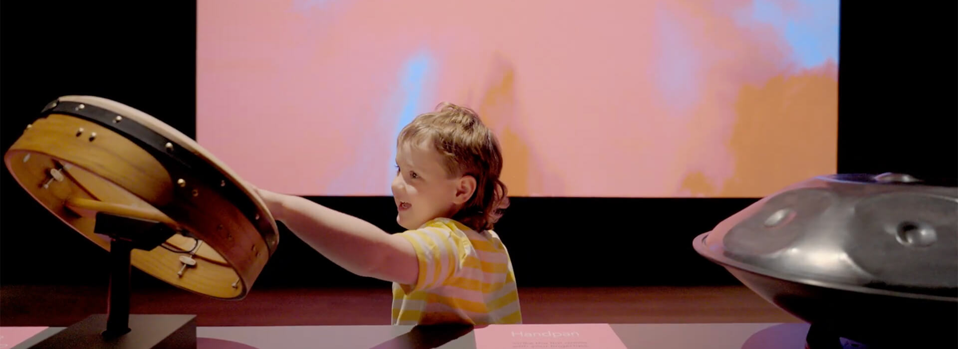 A young child plays a drum in an interactive art experience