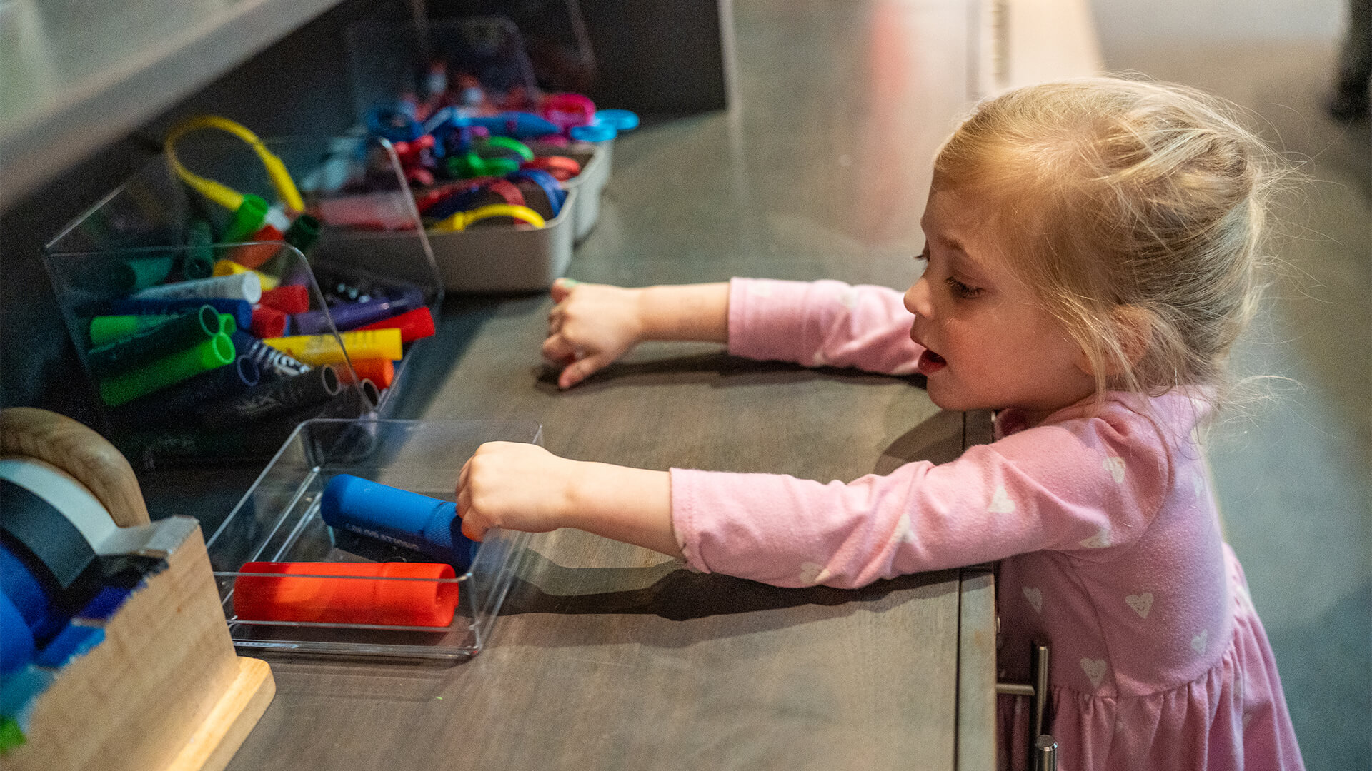 A young child reaches for artmaking supplies