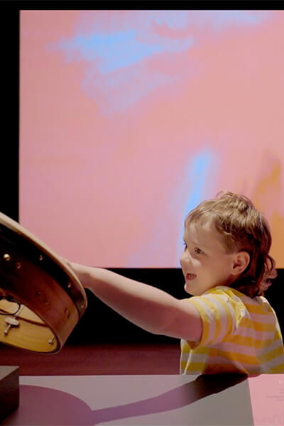 A young child plays a drum in an interactive art experience