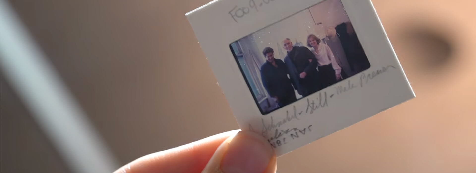 A person holds up a slide photo of 3 people